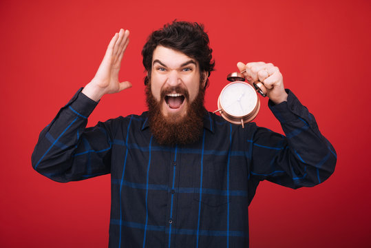 Photo of bearded man, holding a vintage clock, worried about time left. Time management and discipline.