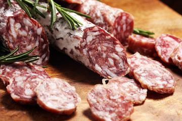 thinly sliced salami sausages on a wooden texture on the background.