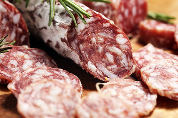 thinly sliced salami sausages on a wooden texture on the background.