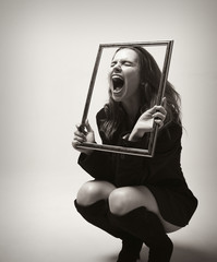 Young girl in a jacket looking through the picture frame and screaming