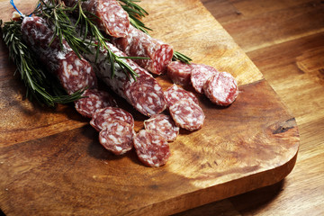 thinly sliced salami sausages on a wooden texture on the background.