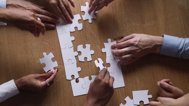 Hands of diverse business team people collaborate assemble puzzle together