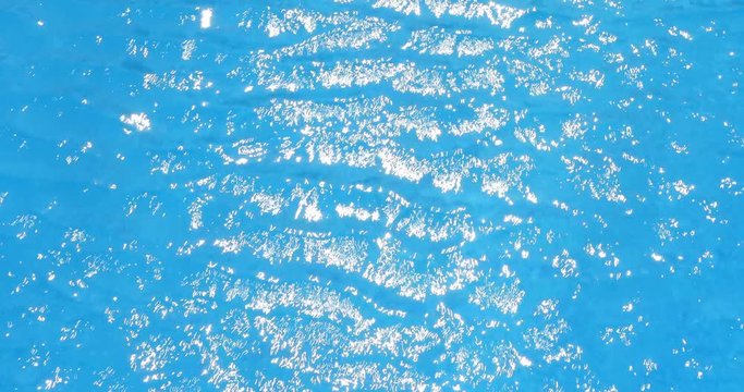 water ripples and sun hightlight in swimming pool, blue background, 4k loop-ready
