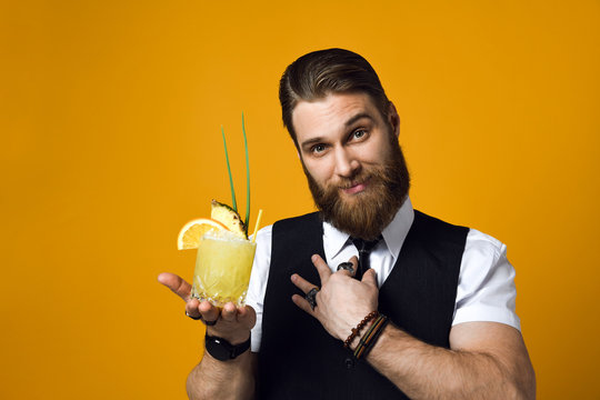 bearded barman with beard holding cocktail in waistcoat