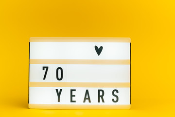 Photo of a light box with text, 70 YEARS, on isolated yellow background