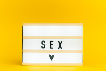 Photo of a light box with text, SEX, on isolated yellow background