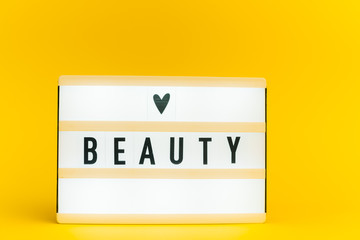 Photo of a light box with text, BEAUTY, on isolated yellow background