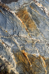 Rough texture in stone, blue, gray, orange, and white, as a nature background