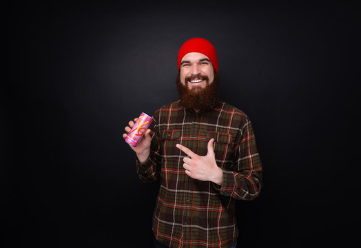 Poratrit of bearded man pounting at Xs energy drink over dark background