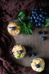 Blueberry muffins with fresh berries and mint leaves in a wooden tray. Copy space.