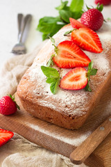 Pound or loaf cake with strawberry and mint on wooden board. Delicious summer dessert.