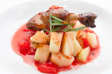 fried duck leg with potatoes and rosemary in red apple sauce confiture on a white background