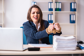 Young beautiful employee tied up with rope in the office 