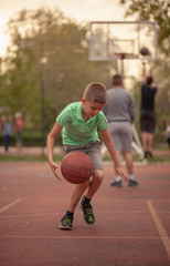 Fototapeta premium One boy, exercising dribbling ball between his legs.