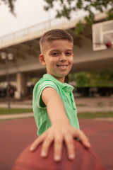 close-up of one boy, smiling to a camera, holding basketball ball in his hands.