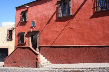 Ancient red facade with stair and wood door with lamp