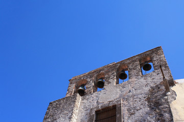 Ancient church facade wit bells and a blue sky