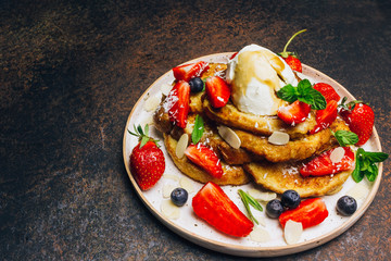 Stecked french toast topped with strawberries, blueberries, mint, ice cream and maple syrup