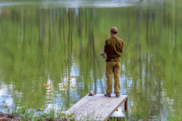 Fototapeta na wymiar Fisherman with a fishing rod on the pond