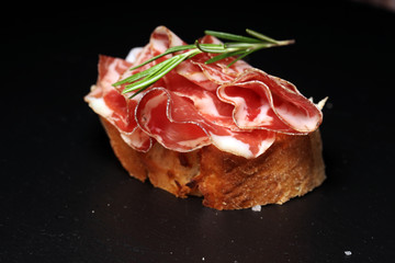 Italian sliced cured coppa with spices. Raw ham. Crudo or jamon with rosemary