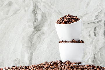 Black coffee in cup and coffee beans on marble background. Top view, space for text