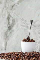 Fototapeta na wymiar Black coffee in cup and coffee beans on marble background. Top view, space for text