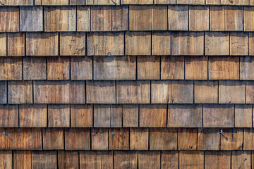 Rough bumpy wood shingle cladding, row of wooden material of small shingle wall facade.