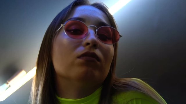 Fashionable girl on the background of a neon lapms clouse-up