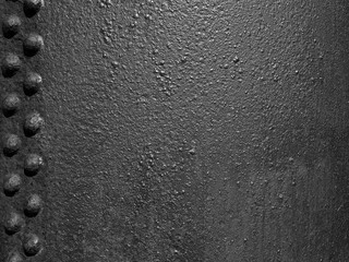 old black rough iron metal surface with grainy texture and lines of rivets