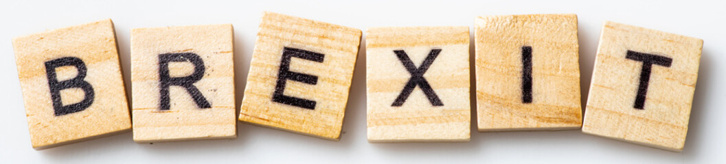 Word BREXIT in uppercase scrabble wooden letters on white background