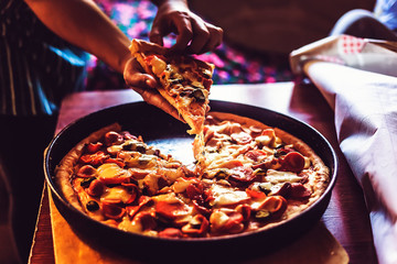 Person's hand taking a piece of pizza