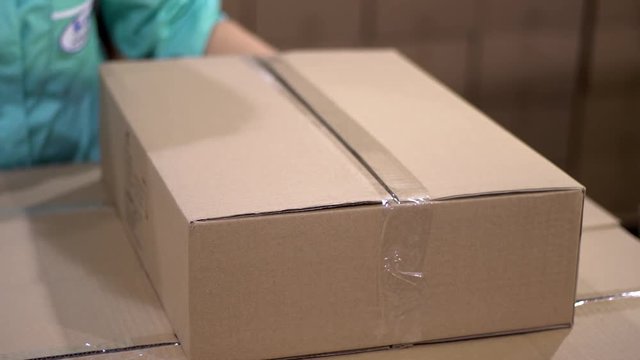 Warehouse Worker Finishes Order, Sealing Cardboard Boxes Ready for Shipment. puts the cardboard box in the frame and finishes the formation of sending packages.