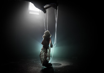 Concept of manipulation. Hand holds strings for manipulation. The hand controls the puppet strings on a dark foggy background.