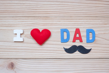 I Love DAD text with red heart shape and mustache on wooden background. Happy Father's Day and International Men's Day concepts