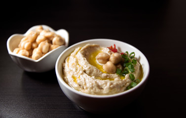 Hummus and chickpea on black background. Selective focus.