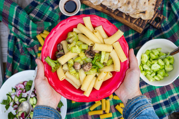 Woman hands holds Pasta with vegetables, Italian macaroni on plate. Vegetarian vegan healthy food. Top above view