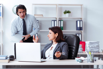 Obraz premium Old female boss and young male employee in the office 