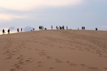 young woman relaxing at white sand dunes on sunset background