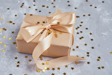 Gift box with golden bow and confetti, close up