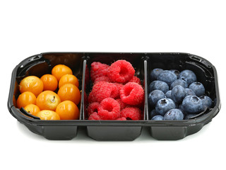raspberries, blueberries and berries of physalis in black container isolated on white background