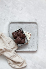 chocolate candy with nuts and dates in gift box on white marble background with copy space