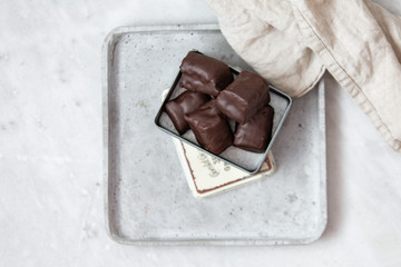 chocolate candy with nuts and dates in gift box on white marble background with copy space