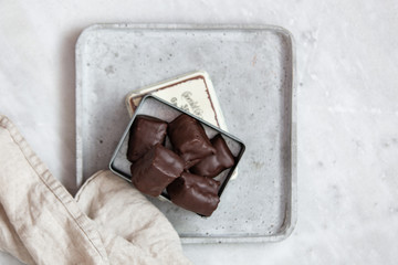 chocolate candy with nuts and dates in gift box on white marble background with copy space