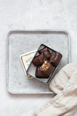 chocolate candy with nuts and dates in gift box on white marble background with copy space
