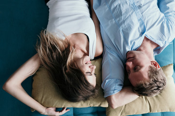 top view of couple looking at camera and smiling while lying in bed