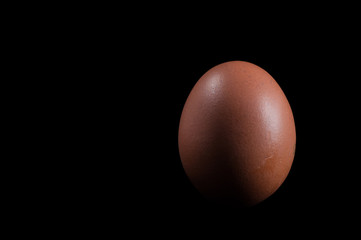 Brown chicken egg on a black background, isolate .