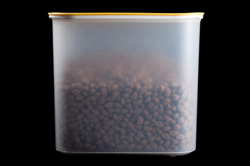 Dry dog food in an airtight container on a black background, isolate.