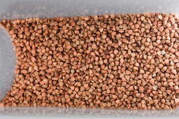 Raw buckwheat in kitchen container  .