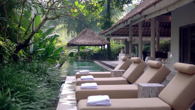Row of lounging chairs on pool terraces in exotic hotel. Outside area with pool