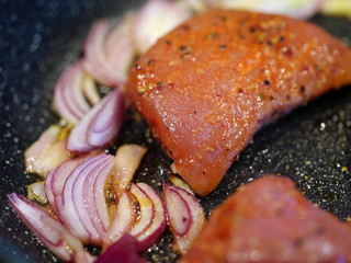 close up of raw fresh marinated meat with red onions in a pan